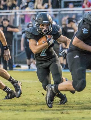 Sharks running back Zach Walton (2) runs through a hole in the offensive line against Wolfson last Friday. Walton carried the ball six times for 46 yards in the win. (photo by Mark Calvin)
